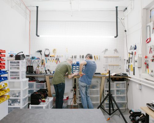 Two male engineers stand at a work bench working on electronics