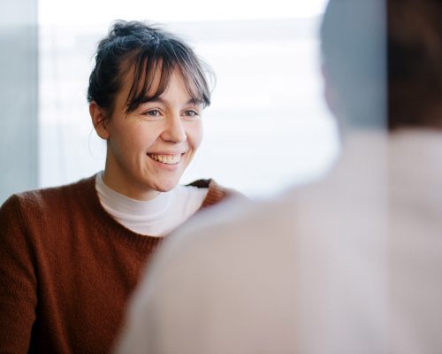 A young caucasian woman in conversation with a male colleague in an office