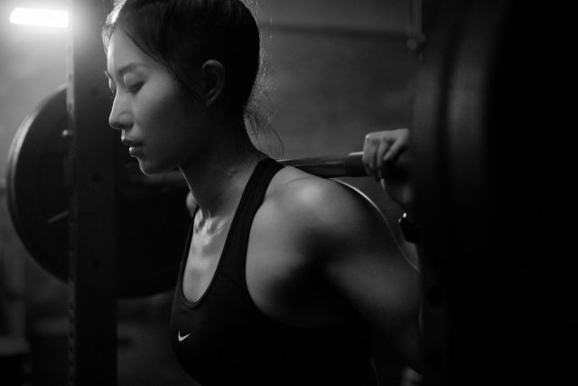 Asian woman working out with barbell in Vancouver indoor gym wearing nike pro clothing