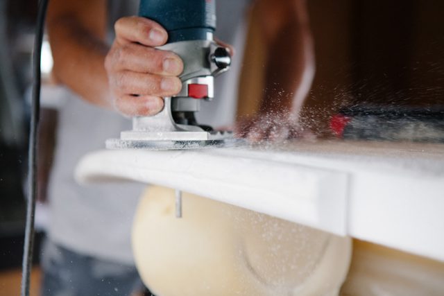 Close up detail of a power tool cutting a surfboard form